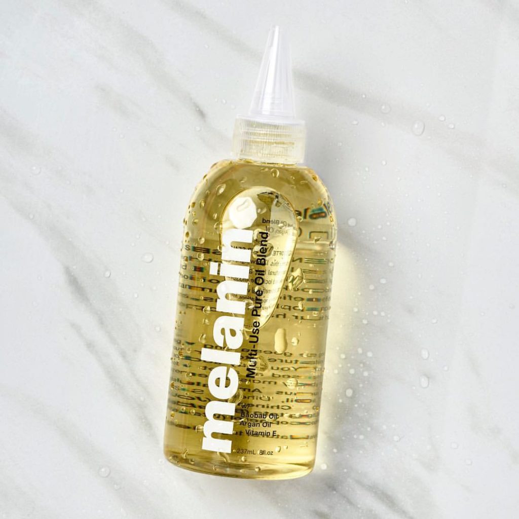 The Melanin Haircare Signature Multi-use pure oil blend in a 8oz applicator bottle, displayed on a marble background for aesthetic purposes. 
